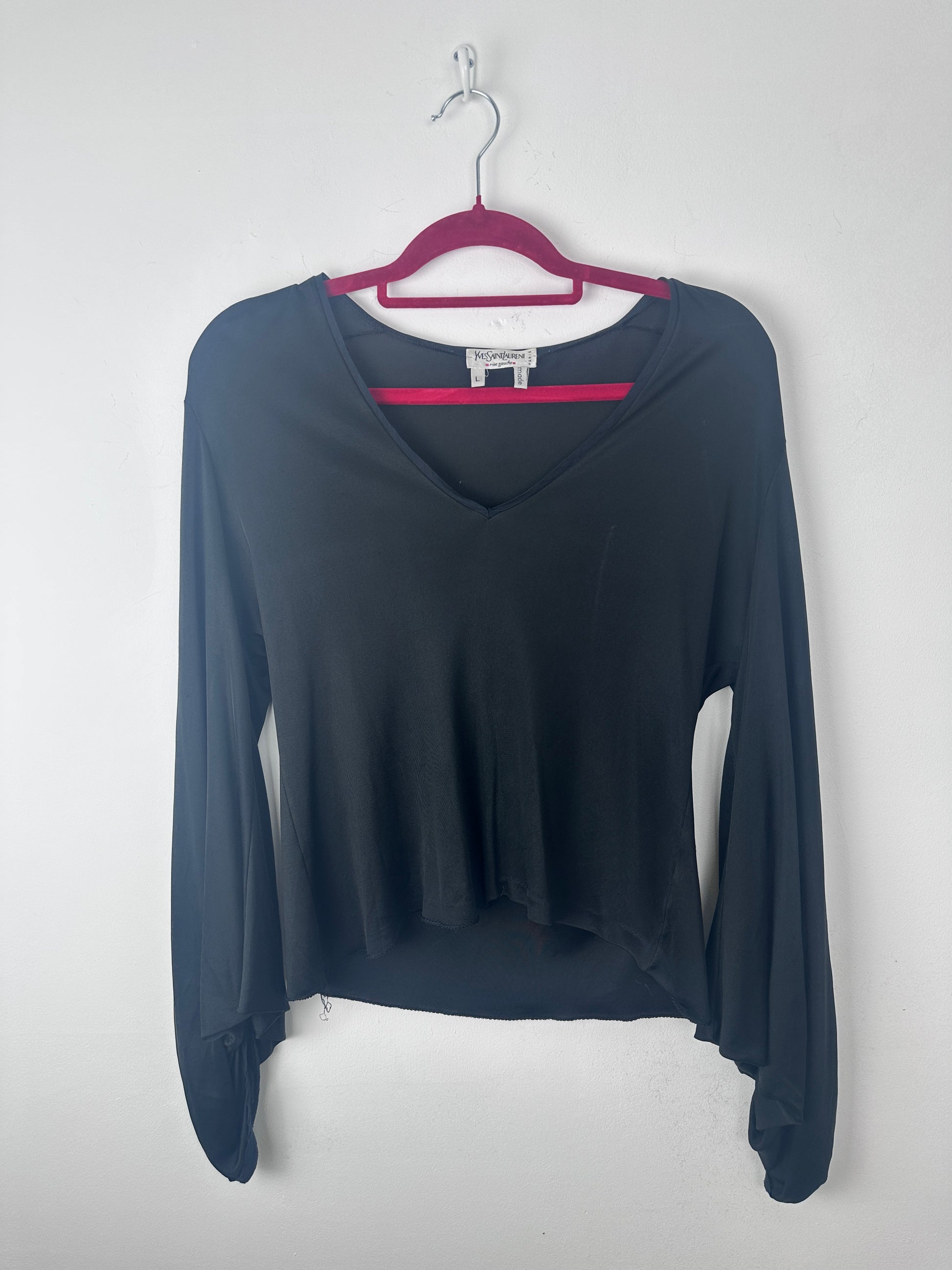 A long-sleeve dark navy blue top with a split neckline and magenta trim, hanging on a magenta hanger against a light gray background.