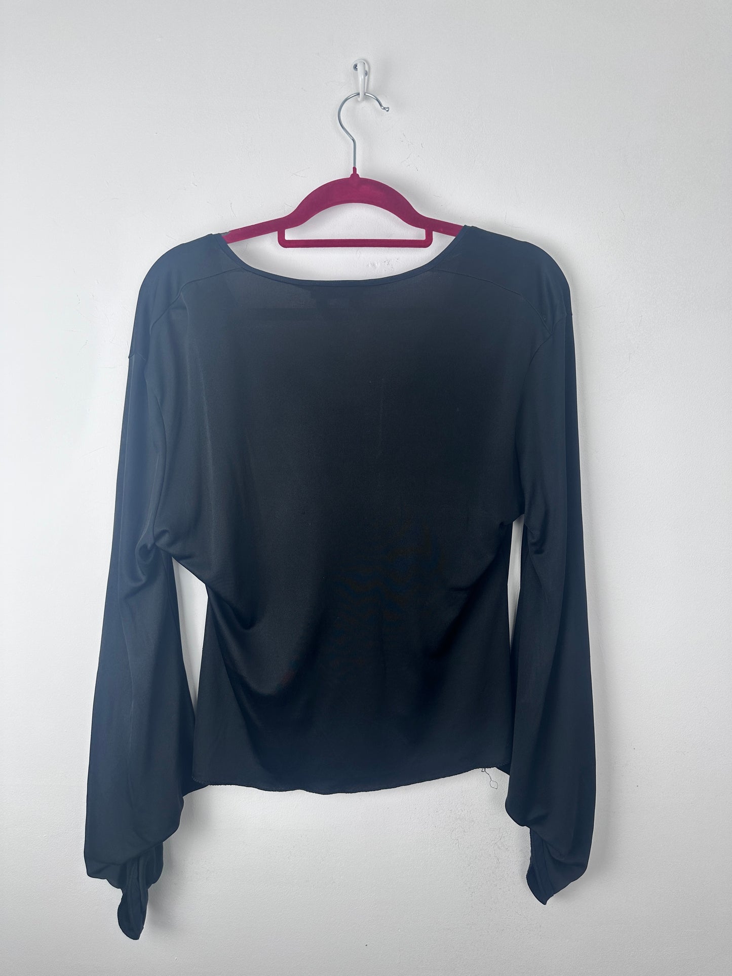 A dark navy blue long-sleeve top hanging on a magenta hanger against a plain white background.
