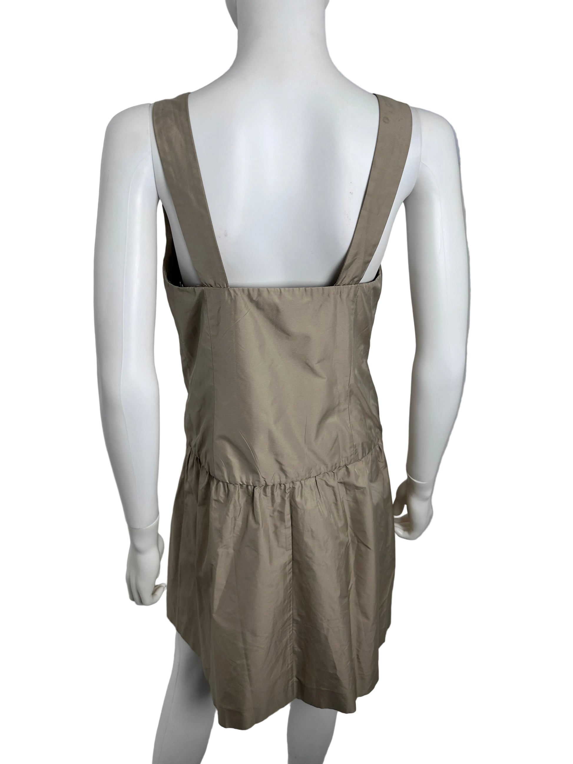 Mannequin wearing a beige dress with a strap on a plain background